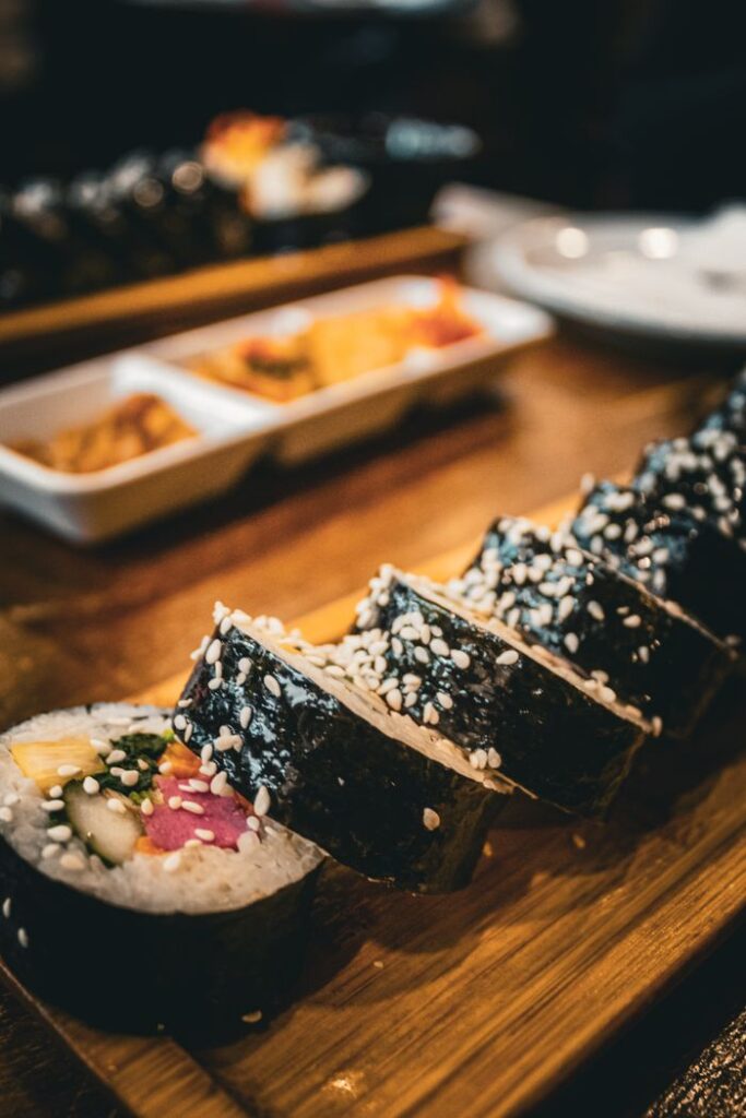 Close-up of sushi rolls with sesame seeds served on a wooden board, perfect for culinary themes.